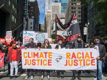 A group of protesters with a sign that says climate justice is racial justice
