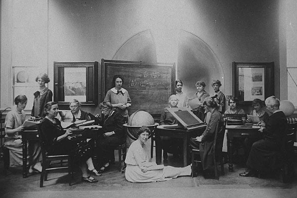 A late 1800s black and white photo of women in a classroom with blackboards